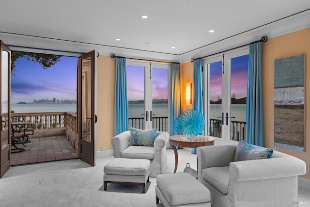 carpeted living room with recessed lighting, a water view, and french doors