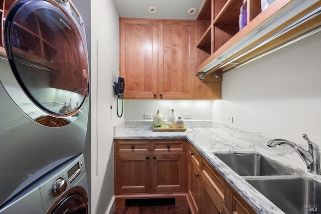 laundry area with cabinet space, stacked washer / dryer, and a sink