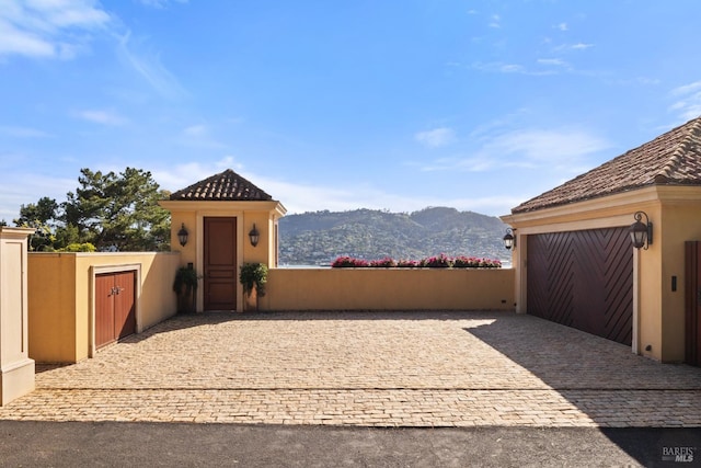 exterior space with fence, driveway, a gate, and a mountain view