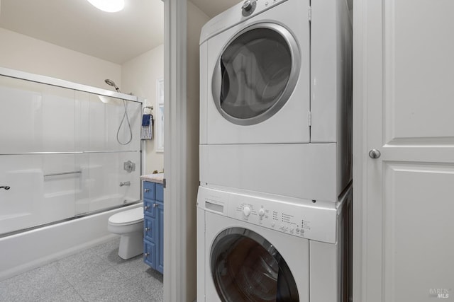 clothes washing area featuring stacked washer and dryer, tile patterned floors, and laundry area