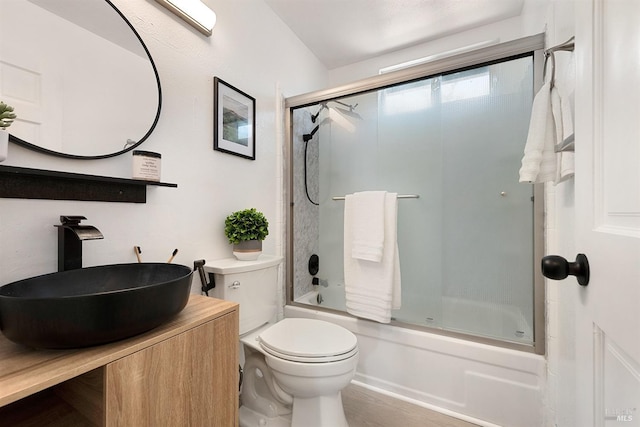full bathroom with toilet, vanity, and bath / shower combo with glass door