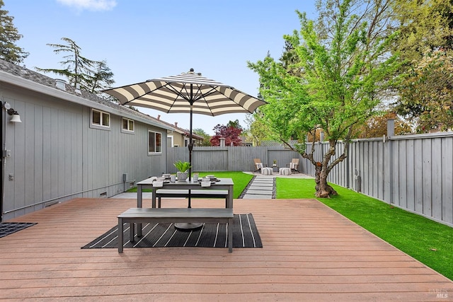 wooden deck featuring a fenced backyard, outdoor dining space, and a lawn