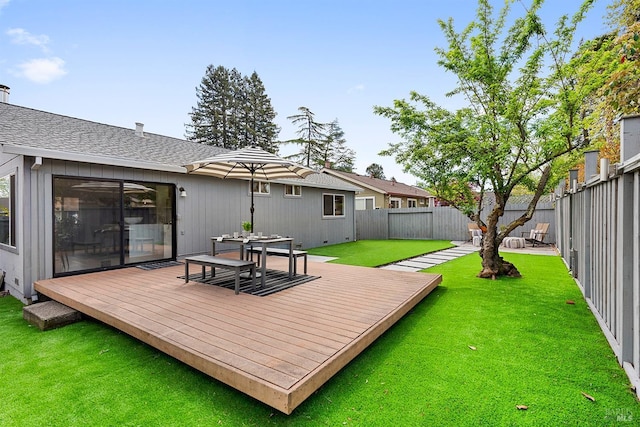 rear view of house with a fenced backyard, a yard, and a deck