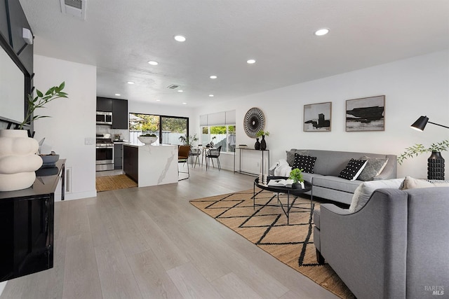 living area with recessed lighting, visible vents, and light wood-type flooring