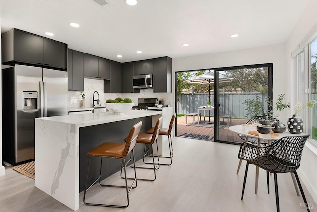 kitchen featuring a healthy amount of sunlight, recessed lighting, dark cabinetry, and stainless steel appliances