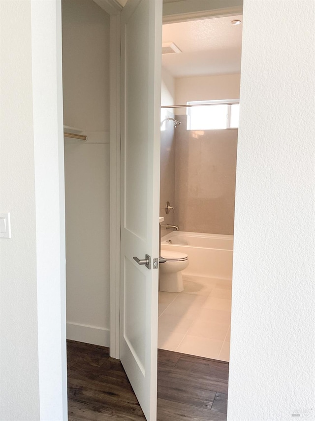 full bathroom featuring washtub / shower combination, toilet, and wood finished floors