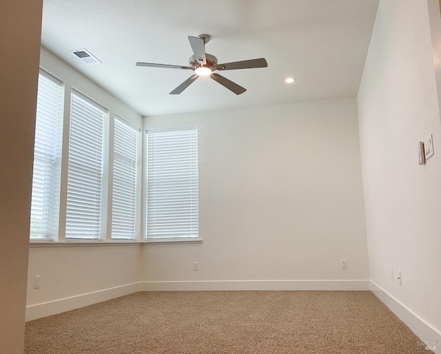 spare room with light carpet, a ceiling fan, visible vents, and a wealth of natural light
