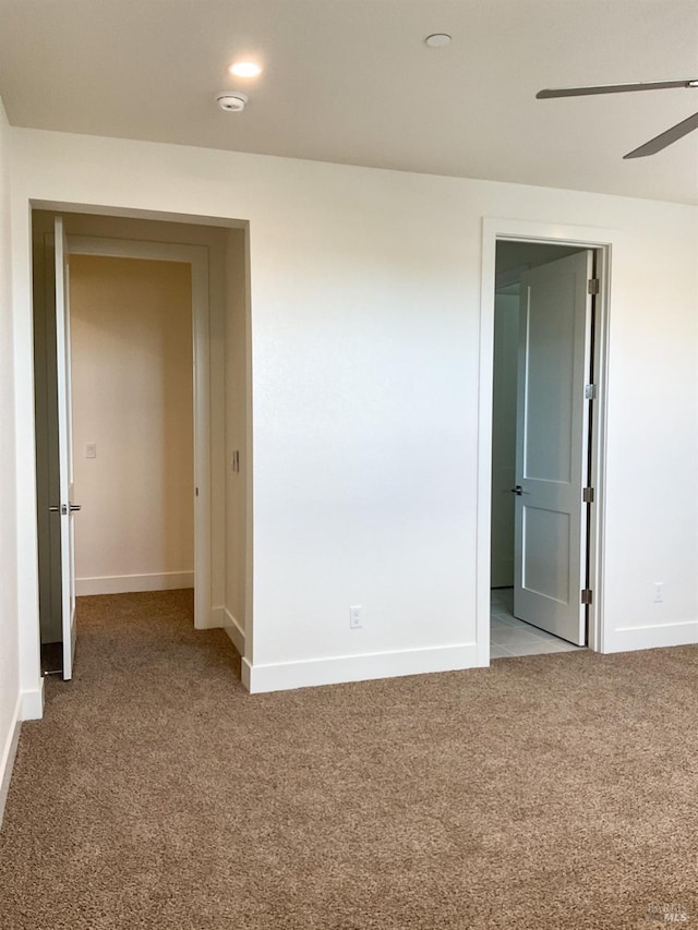 carpeted spare room with baseboards and ceiling fan