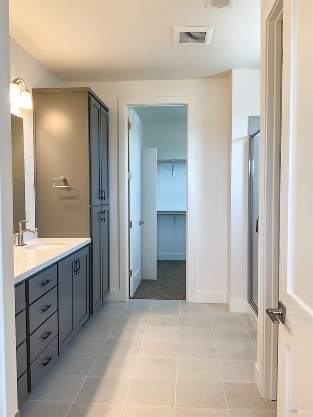 bathroom featuring vanity, baseboards, tile patterned flooring, a shower stall, and visible vents