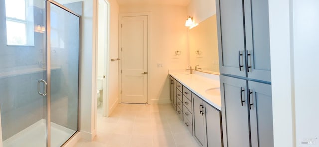 full bath with a shower stall, toilet, tile patterned floors, double vanity, and baseboards