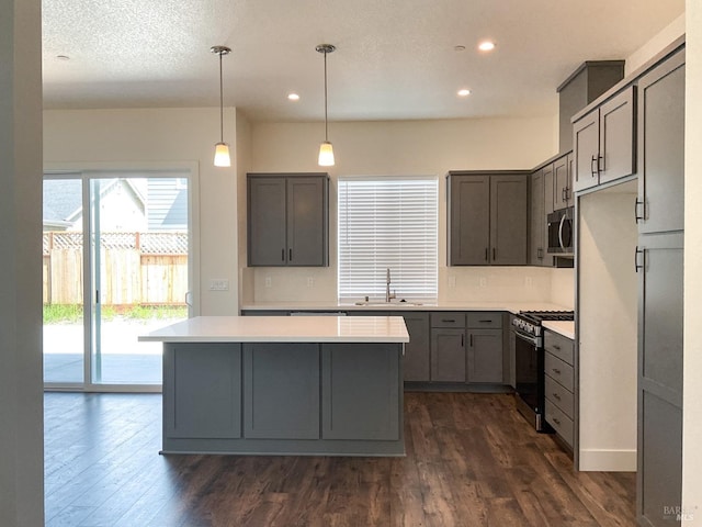 kitchen with recessed lighting, appliances with stainless steel finishes, light countertops, a sink, and dark wood-style floors