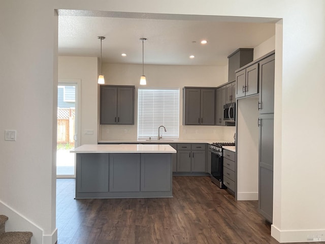 kitchen with a sink, gray cabinets, appliances with stainless steel finishes, and dark wood-style floors