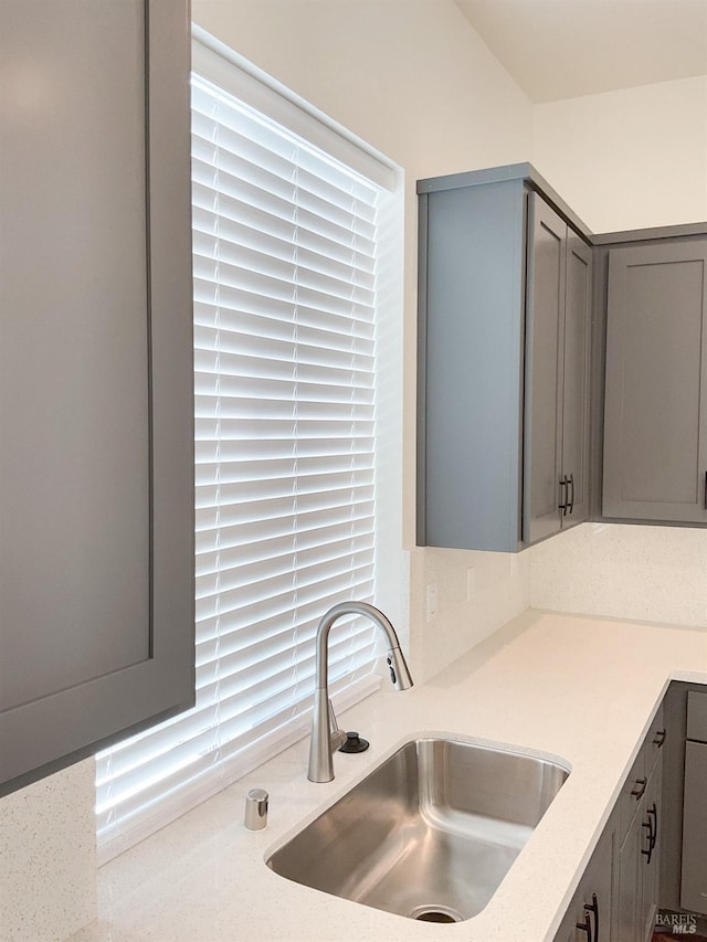 kitchen with a sink, light countertops, and gray cabinetry