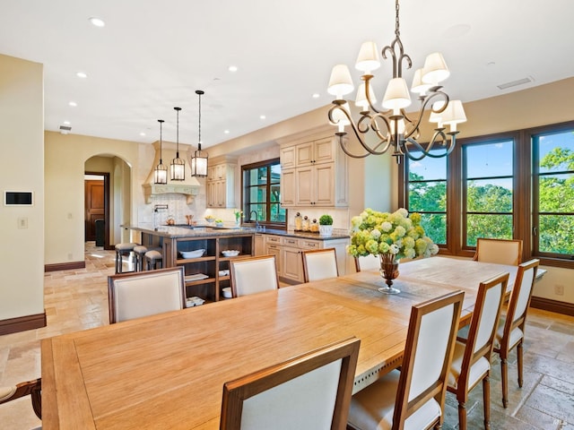 dining area with baseboards, arched walkways, a wealth of natural light, and stone tile floors