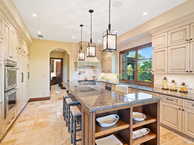 kitchen featuring double oven, arched walkways, open shelves, a sink, and stone tile flooring