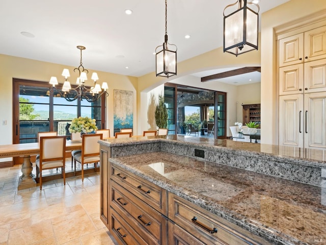 kitchen featuring a chandelier, pendant lighting, stone tile floors, and stone countertops