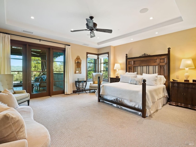 bedroom featuring a tray ceiling, access to outside, light colored carpet, and visible vents