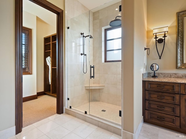 full bathroom with baseboards, tiled shower, tile patterned flooring, and vanity