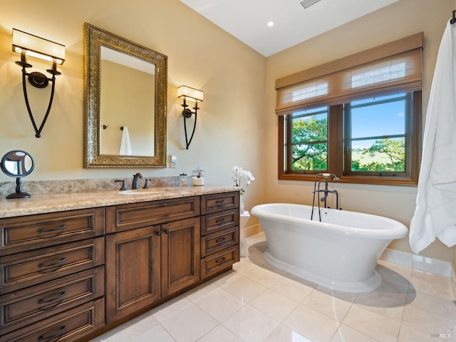 bathroom featuring tile patterned flooring, vanity, baseboards, and a soaking tub