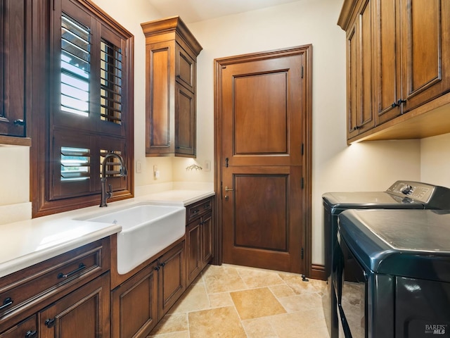 laundry room with washer and dryer, stone finish floor, a sink, and cabinet space