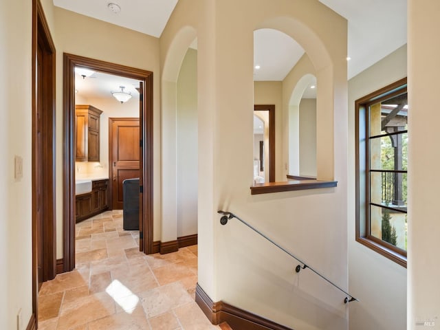 hallway with baseboards, arched walkways, and stone tile floors