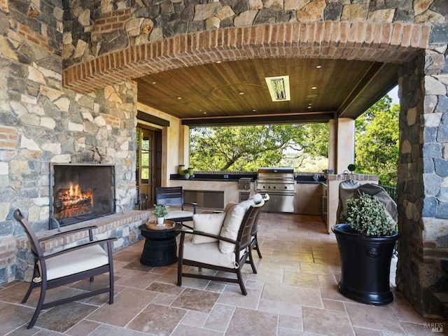 view of patio with grilling area, an outdoor stone fireplace, and area for grilling