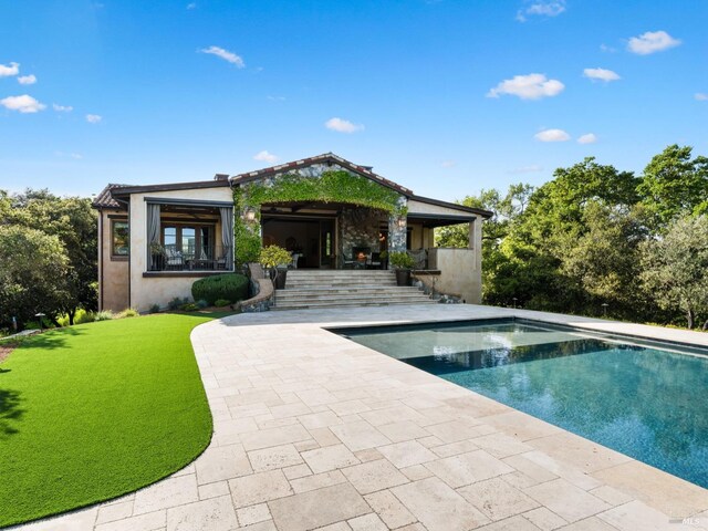 back of property featuring an outdoor pool, a yard, a patio, and stucco siding