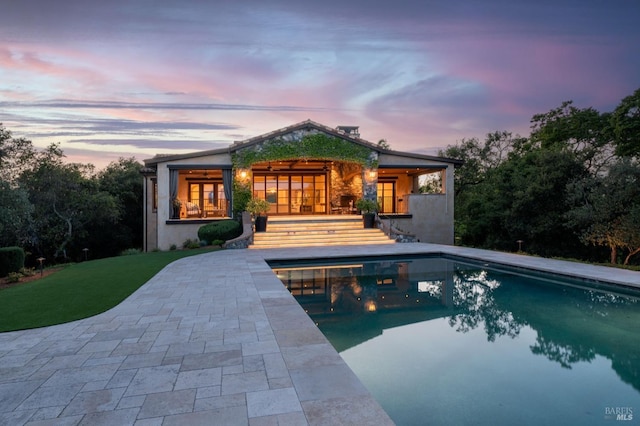 rear view of house with a patio, an outdoor pool, and stucco siding