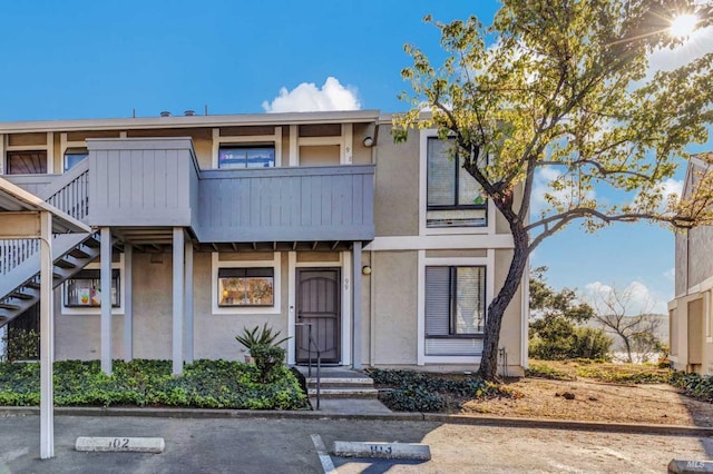 900 Southampton Rd Unit 99, Benicia, CA 94510 - view of front of house with stairway, uncovered parking, a balcony, and stucco siding