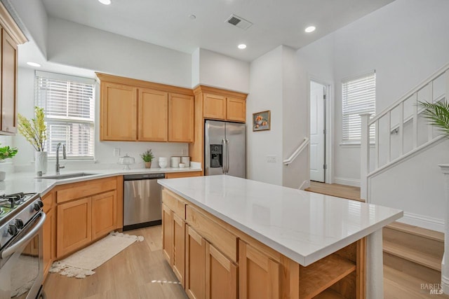 kitchen with light wood-type flooring, visible vents, a kitchen island, appliances with stainless steel finishes, and a sink