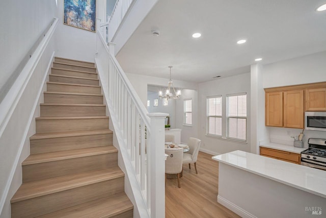 stairs featuring baseboards, wood finished floors, recessed lighting, and a notable chandelier