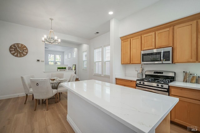 kitchen with visible vents, a kitchen island, a chandelier, stainless steel appliances, and light wood finished floors