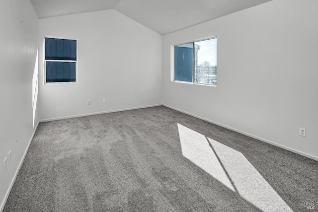 carpeted spare room with baseboards and vaulted ceiling