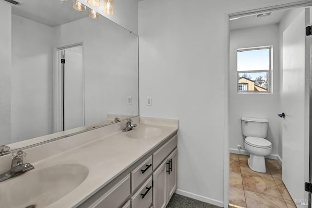 bathroom with double vanity, visible vents, baseboards, and a sink
