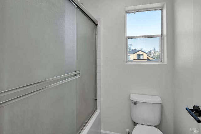 bathroom with toilet, shower / bath combination with glass door, and baseboards