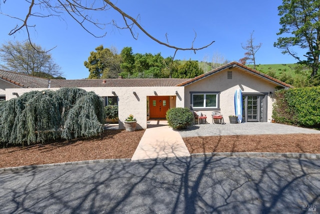 view of front of property with a tiled roof, a patio area, and stucco siding