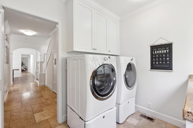 clothes washing area with washing machine and dryer, arched walkways, cabinet space, and ornamental molding