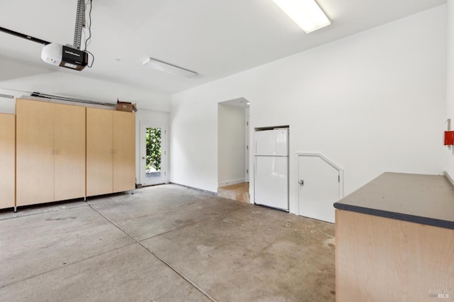 garage with freestanding refrigerator and a garage door opener