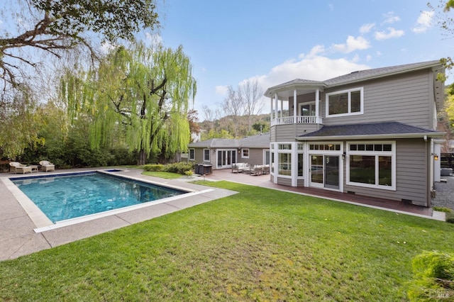 back of house featuring a yard, roof with shingles, a patio area, a balcony, and an outdoor pool