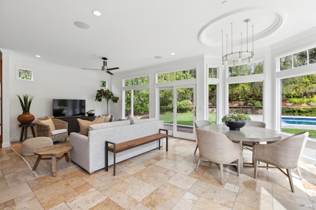 living room with stone tile flooring, crown molding, and a ceiling fan