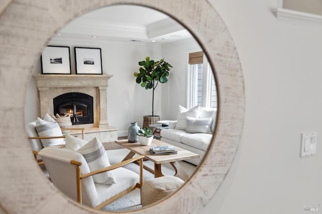 living room with a raised ceiling, arched walkways, ornamental molding, a high end fireplace, and wood finished floors