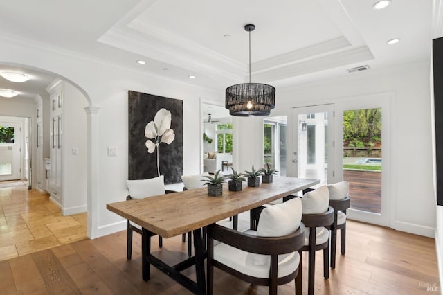 dining space with a tray ceiling, arched walkways, and a wealth of natural light