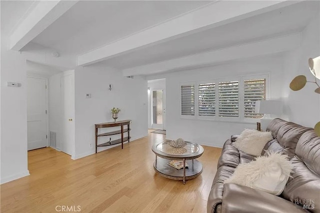living area with light wood finished floors, visible vents, and beam ceiling