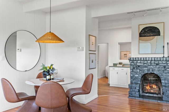 294 Scenic Rd, Fairfax, CA 94930 - dining space featuring rail lighting, light wood finished floors, a lit fireplace, and baseboards