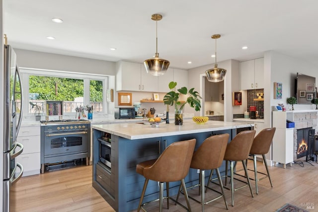 299 Via Barranca, Greenbrae, CA 94904 - kitchen with light countertops, white cabinetry, light wood-style floors, and stainless steel appliances
