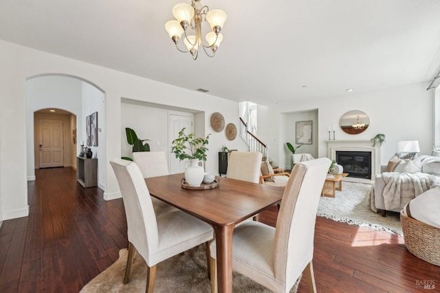 dining space featuring visible vents, arched walkways, a notable chandelier, stairs, and hardwood / wood-style floors