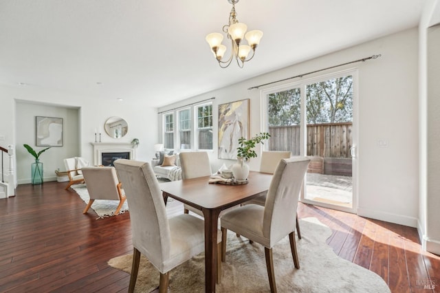 dining area featuring a glass covered fireplace, baseboards, a chandelier, and hardwood / wood-style flooring