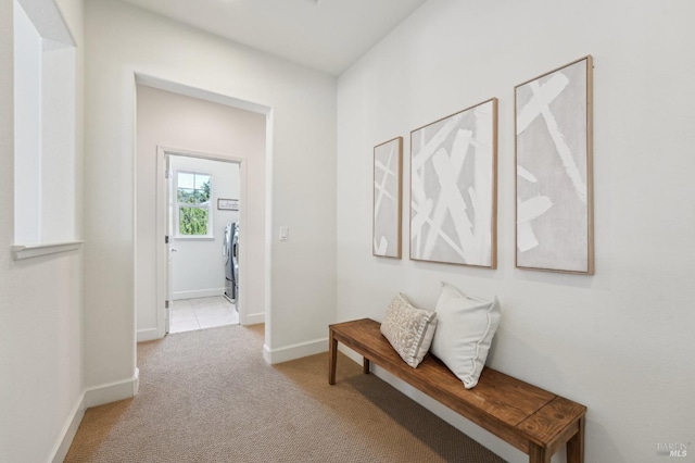hallway featuring baseboards, carpet, and washer / dryer