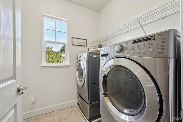 laundry area with baseboards, washer and dryer, light tile patterned flooring, and laundry area