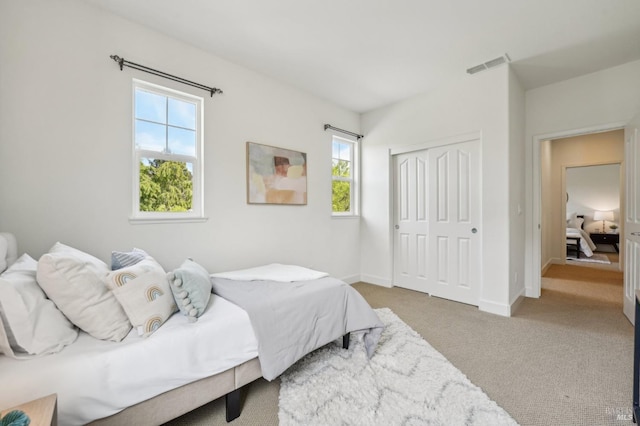 carpeted bedroom with a closet, baseboards, multiple windows, and visible vents